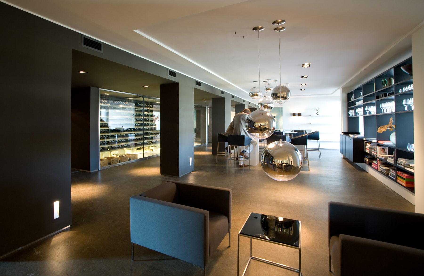 Bar en lounge van hotel Elzenduin met verlichte glazen wijnkast en spiegelende bolarmaturen