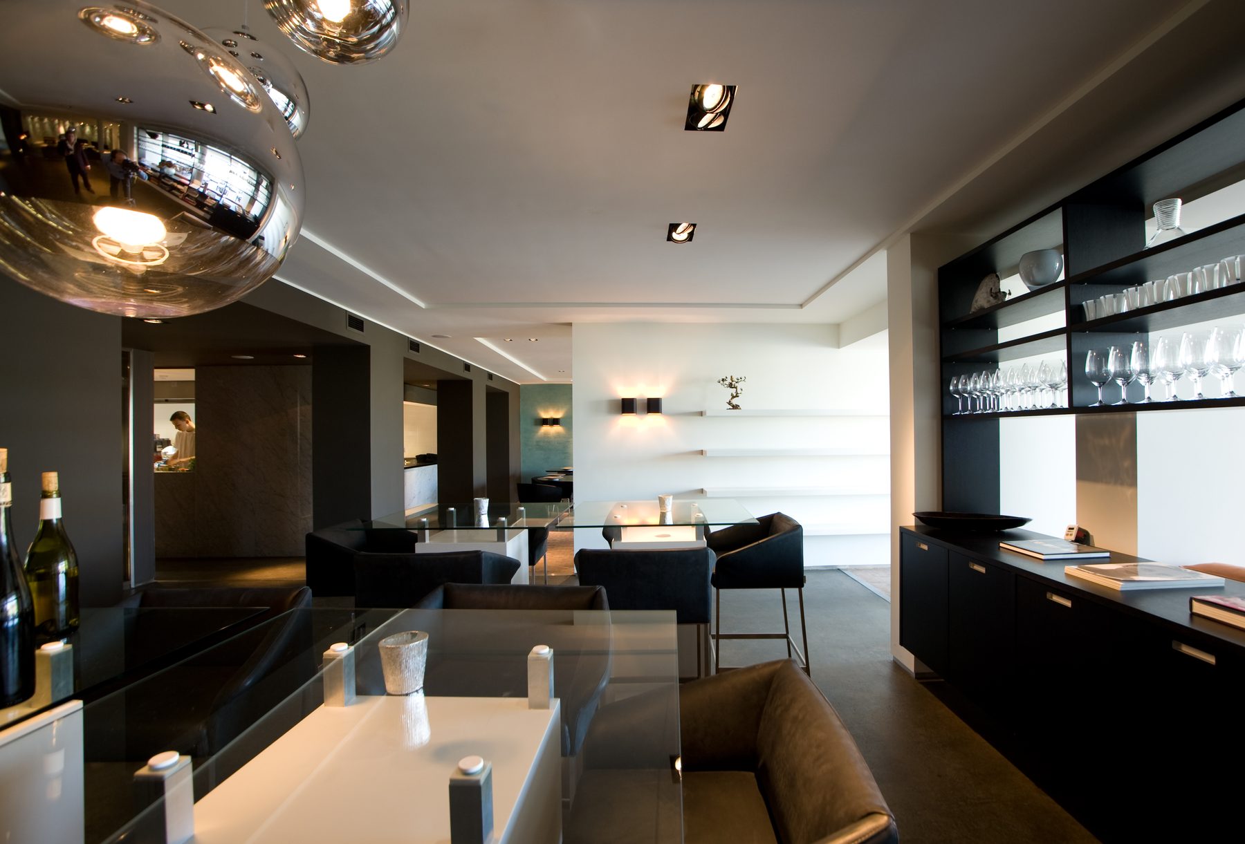 Restaurant van hotel Elzenduin in Ter Heijde met glazen tafels en zicht op de open keuken
