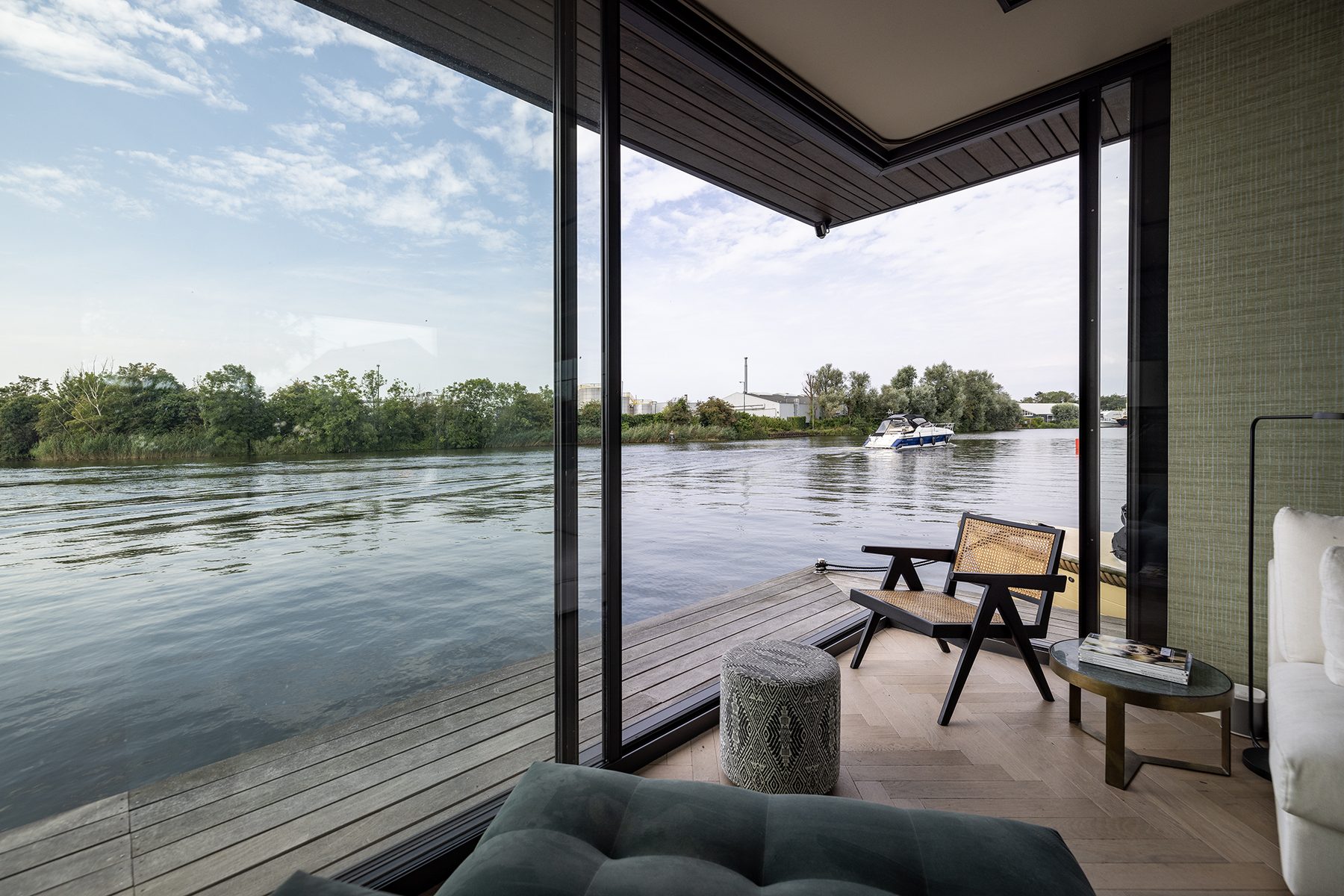 Zitkamer van de woonark met open hoekschuifpui en panoramisch uitzicht over de Vecht
